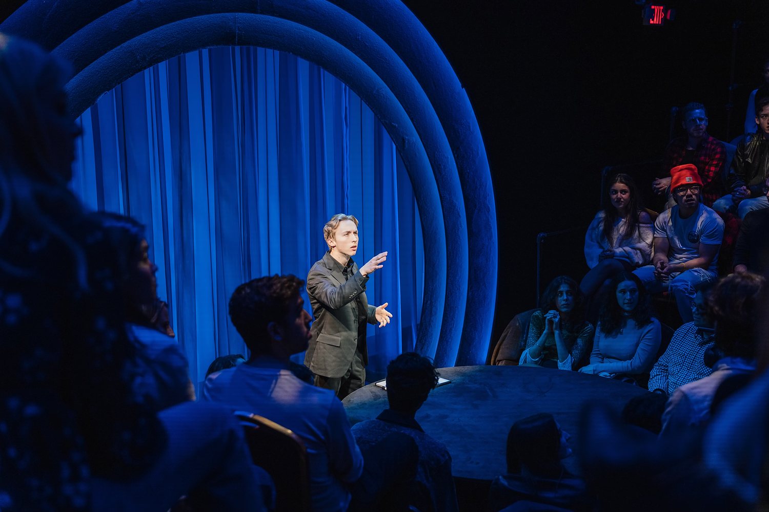 Tom on stage beneath blue arches