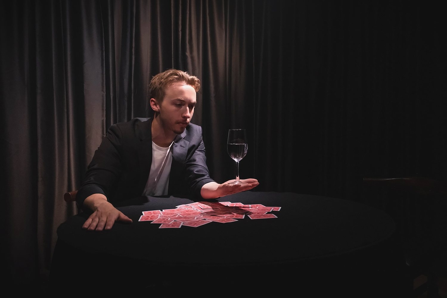 A wine glass balanced on Tom's palm over spread cards