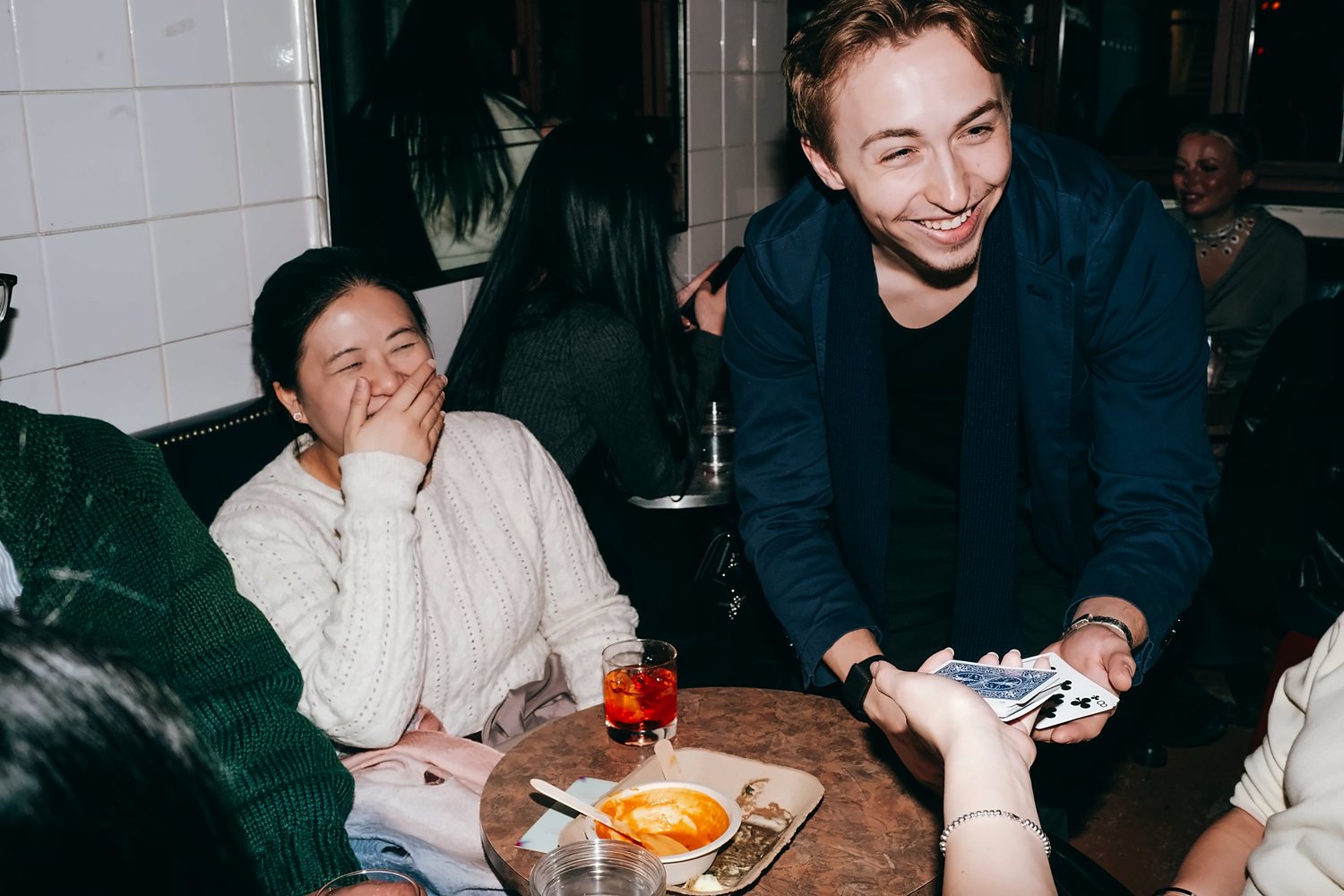 A guest laughing as Tom spreads the deck