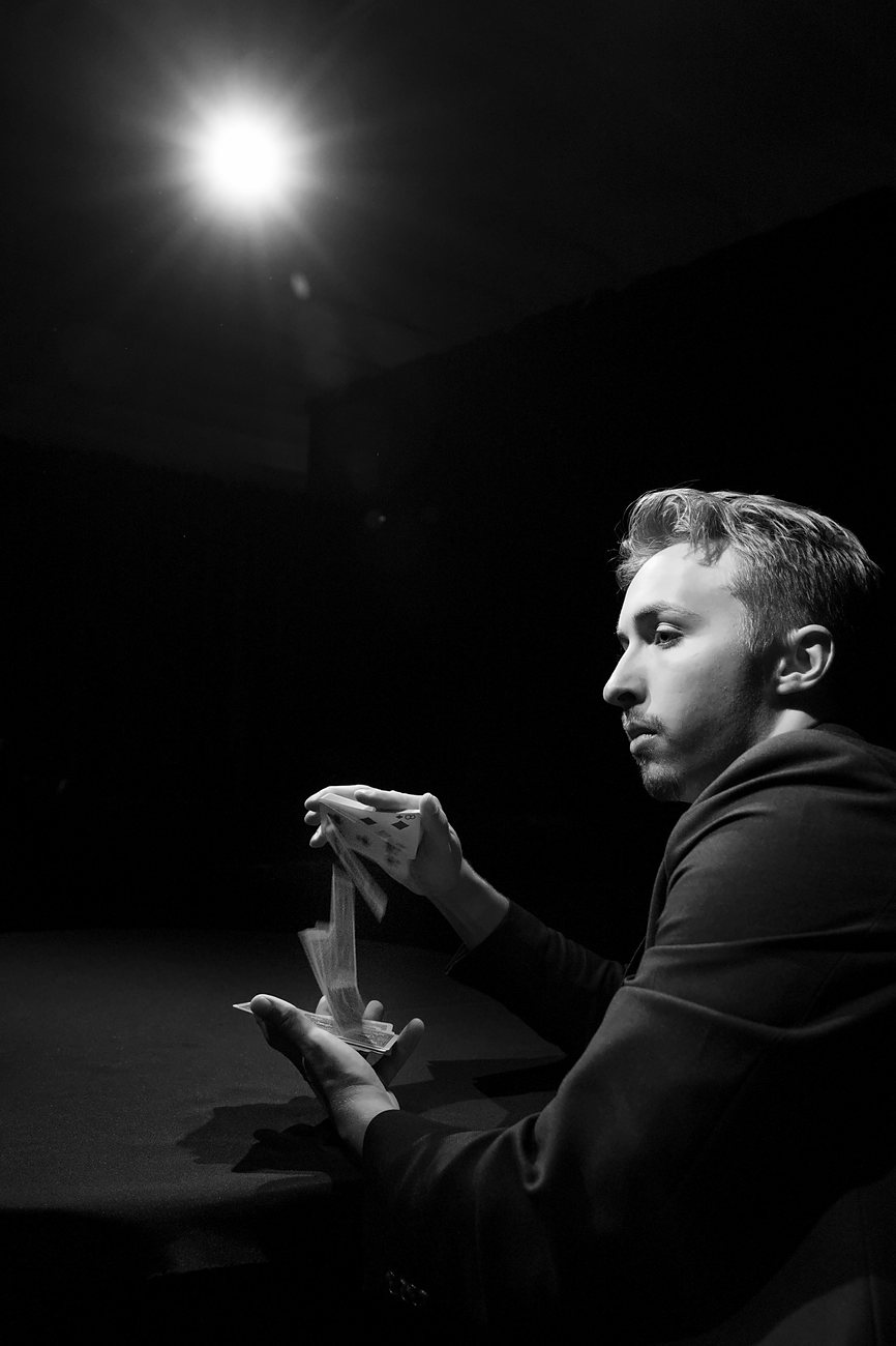 Tom shuffling cards under a spotlight