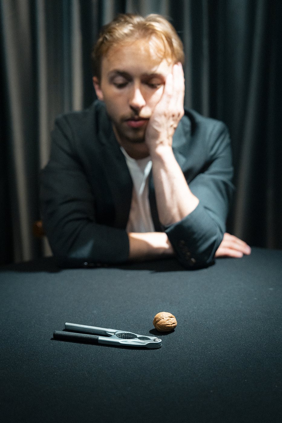 Tom resting his head on his hand beside a walnut and nutcracker
