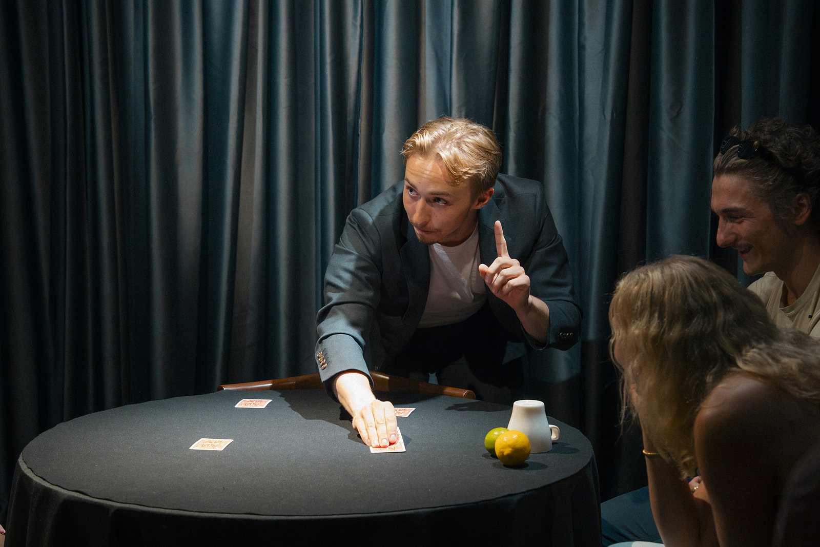 Tom pointing up while sliding a card across the table