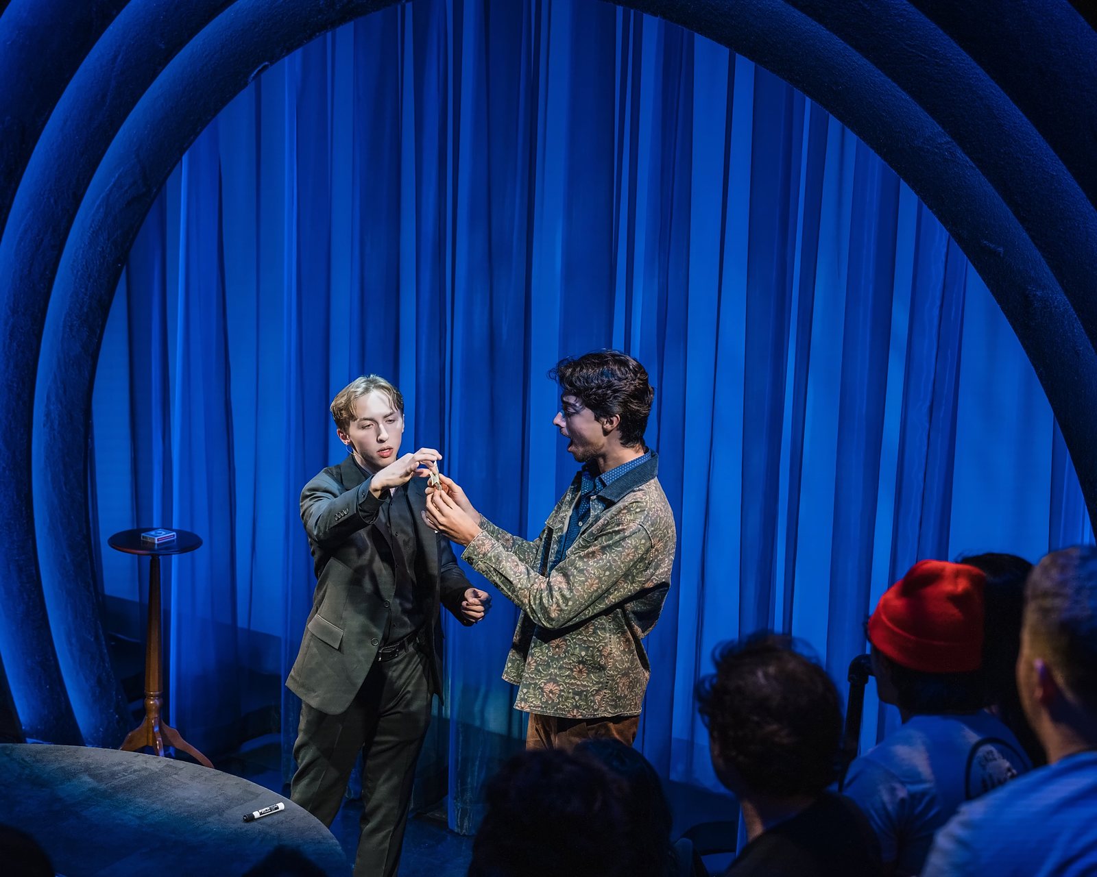 Tom and a volunteer examining a folded bill on stage